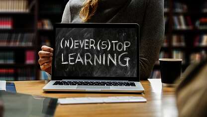 Frau hält Kreidetafel mit der Aufschrift Never Stop Learning