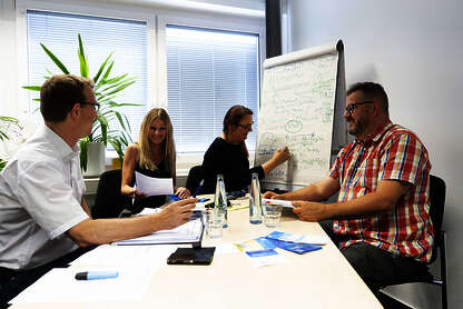 Team des Pflegereferats, bestehend aus 4 Personen, sitzt gut gelaunt an einem Tisch, Frau Esther Braun schreibt etwas auf ein Flipchart