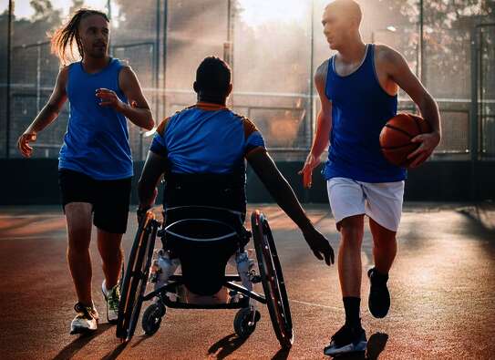 Rollstuhlfahrer nd zwei nicht Behinderte Menschen beim Ballsport