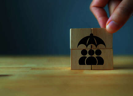 Ein Holzwürfel auf der der Icon-Figuren, die einen Regenschirm halten gemalt sind.